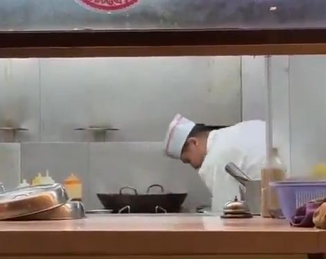 中国のレストラン、料理人が中華鍋で床を掃除するモップを洗う。